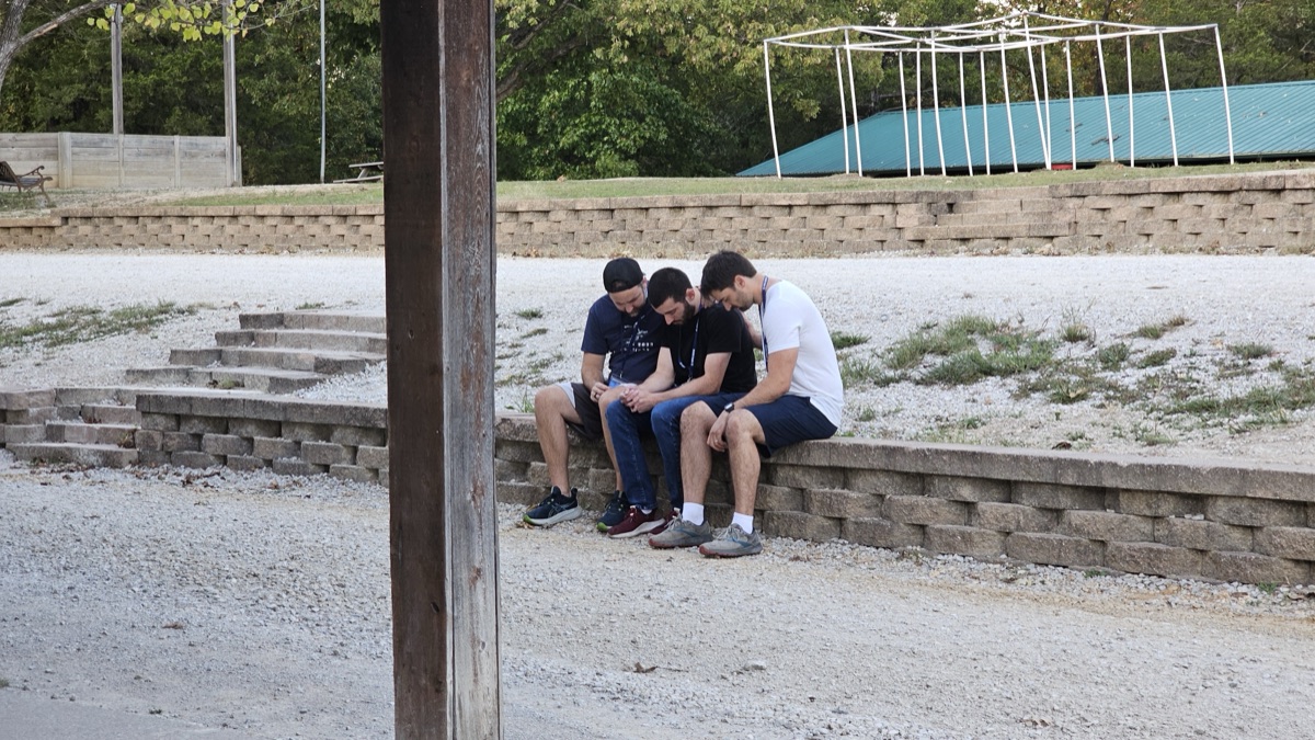Three young men praying together outside