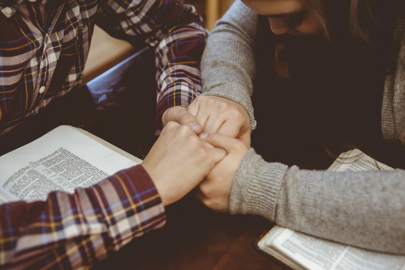 A couple praying together, hands held over open Bibles