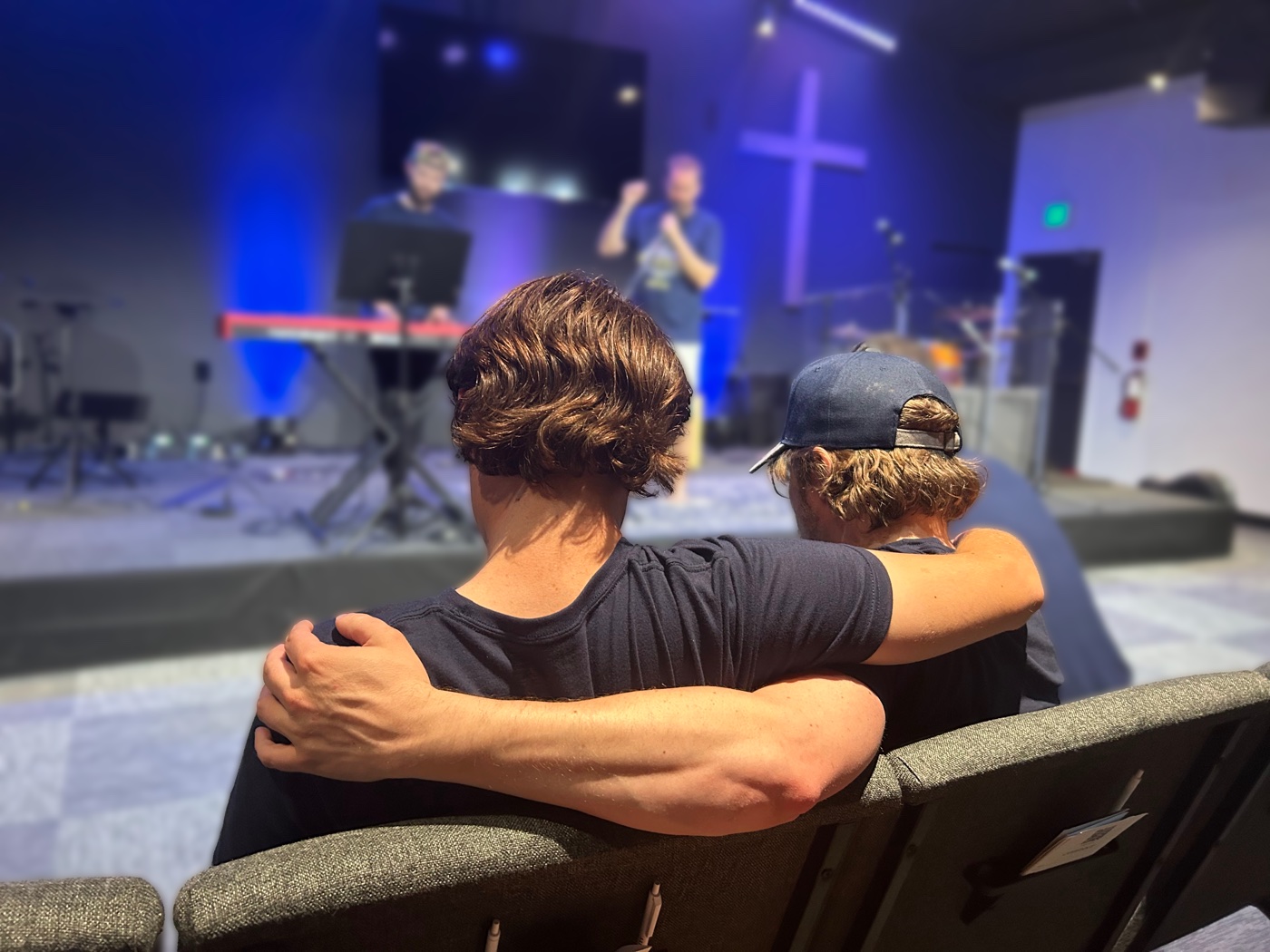 Two friends, one arm around the other, at a HopeCon session